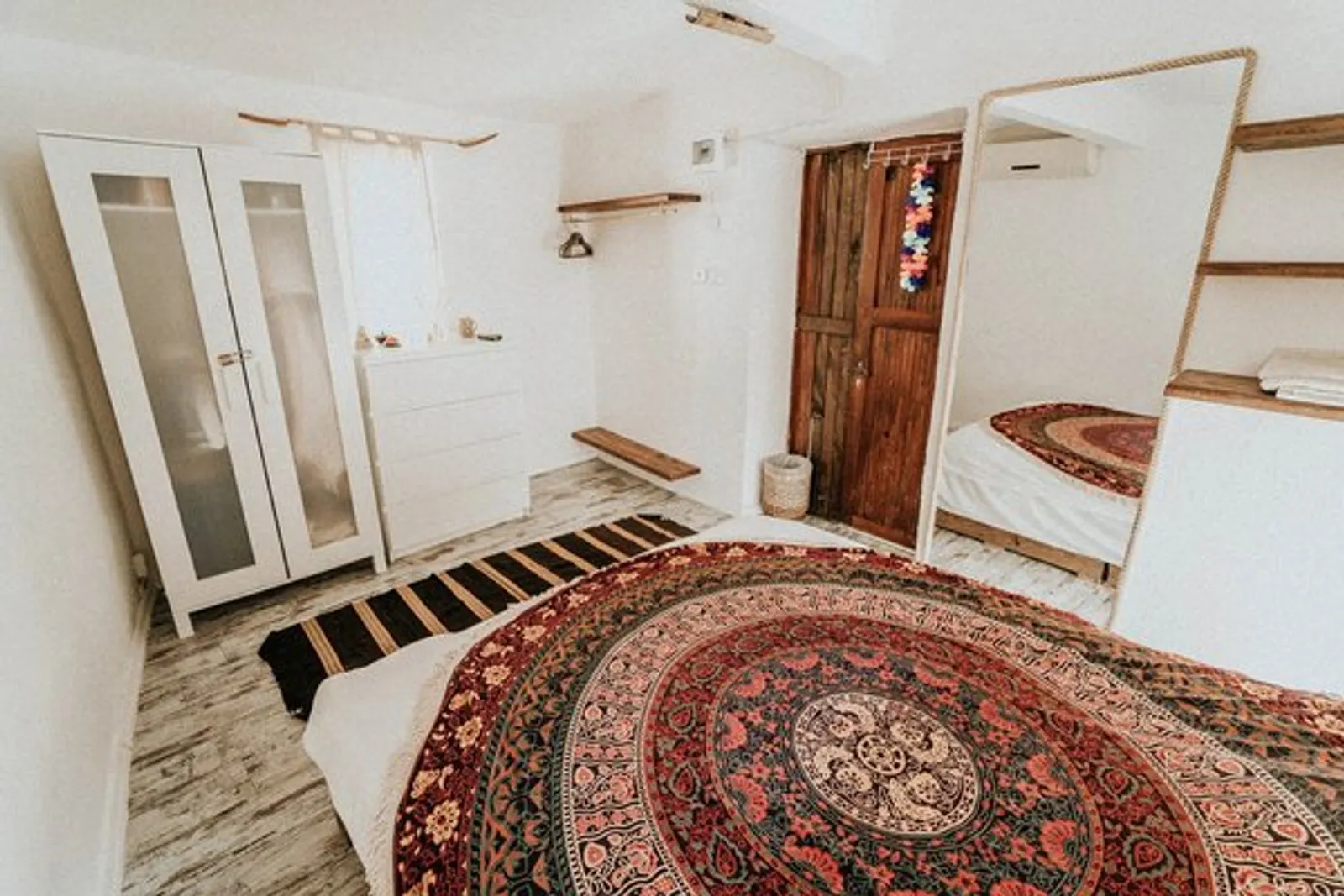 Bungalow: white room with a mirror and a patterned bedspread