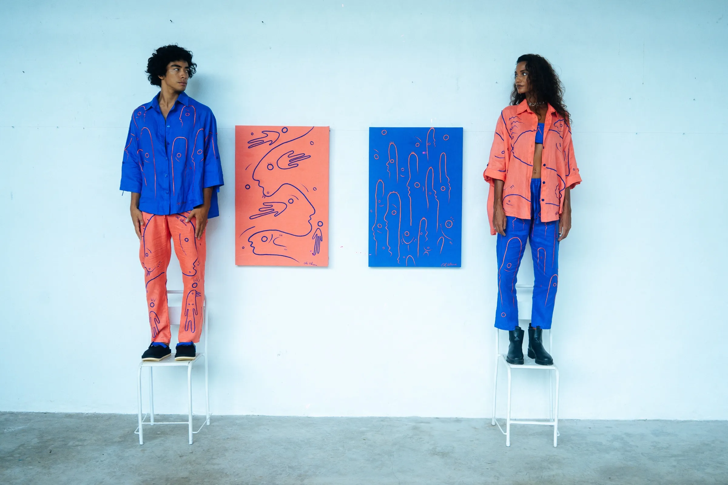 Two people wearing UKENA art garments beside matching artworks.