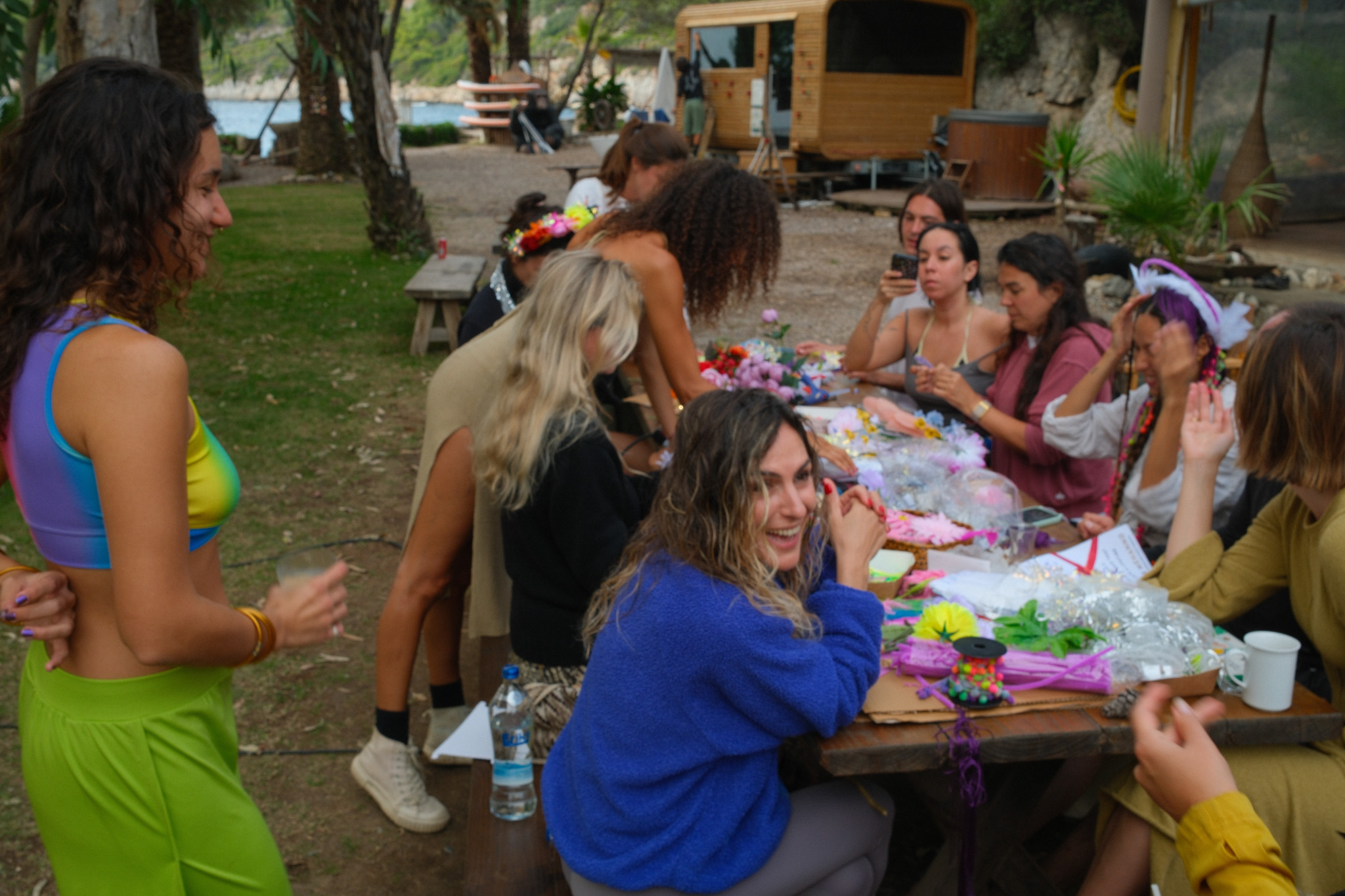 People laughing and making colourful decorations around an outdoor table