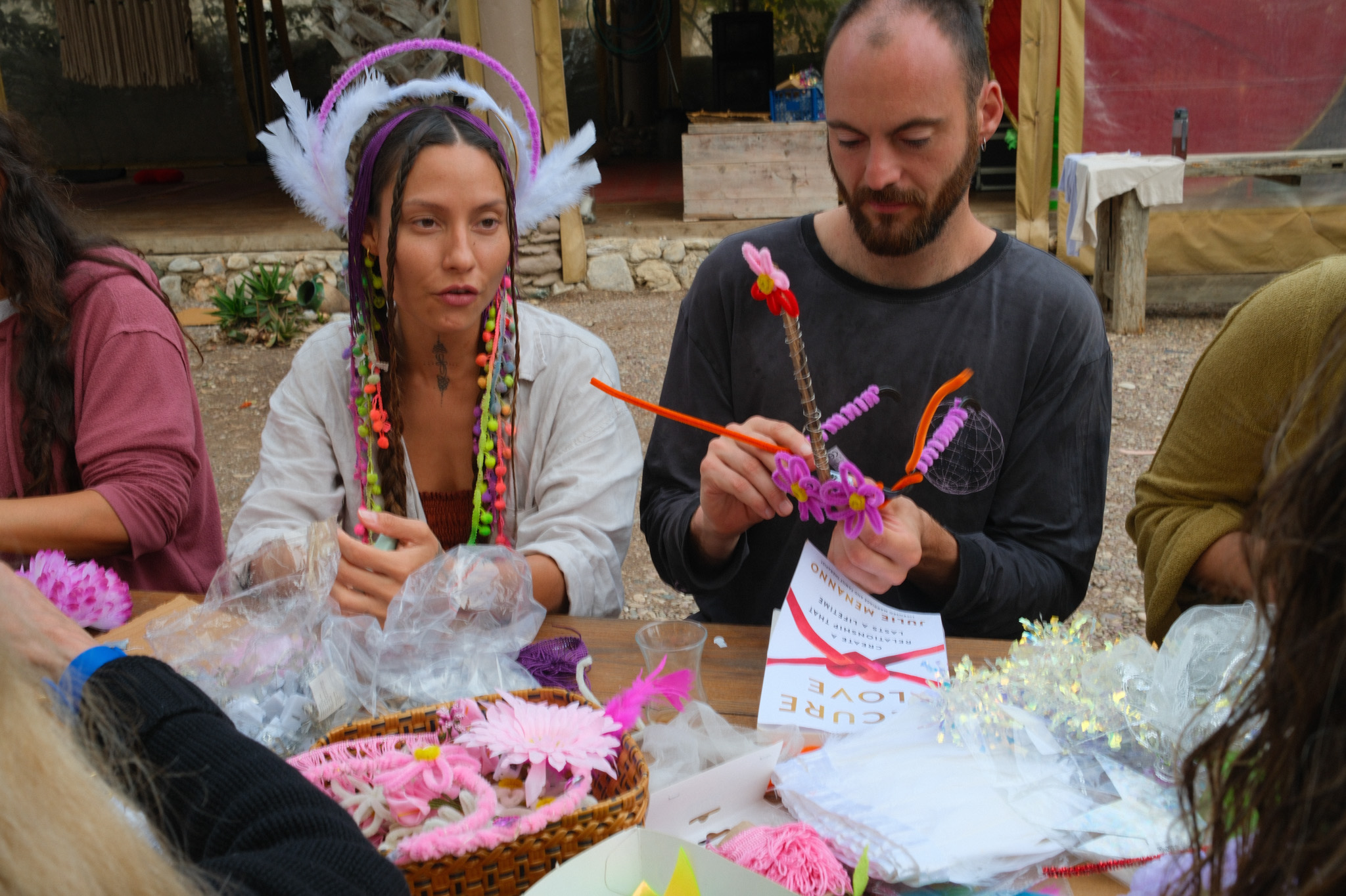 Two participants making colourful wearable decorations at a table