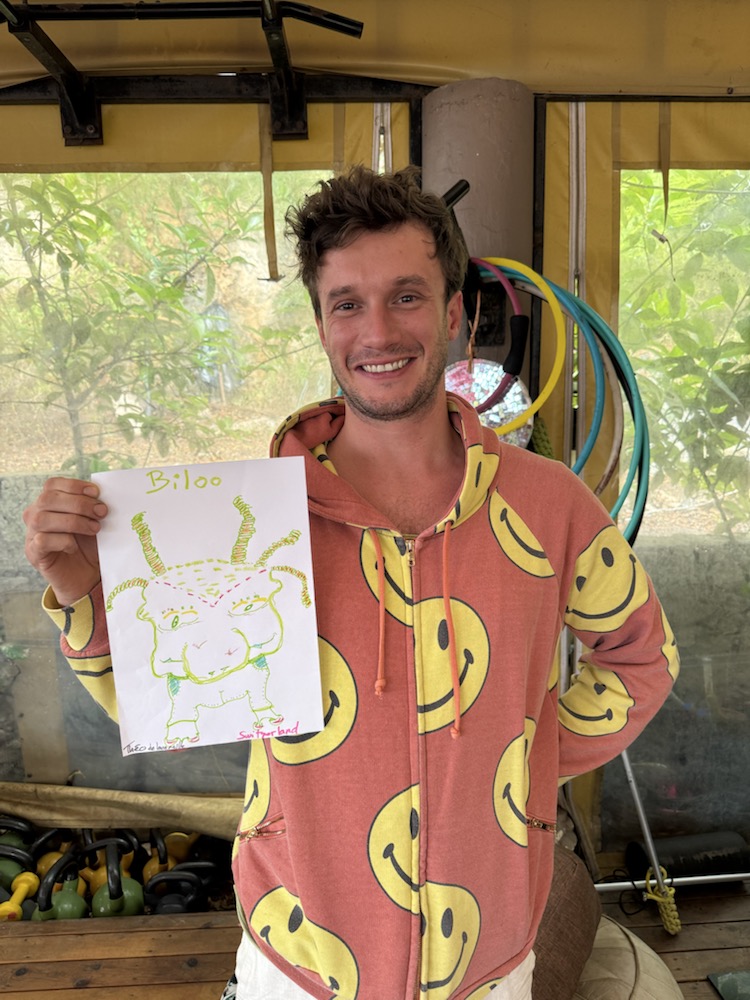 Participant in a patterned shirt holding a yellow-green alien drawing